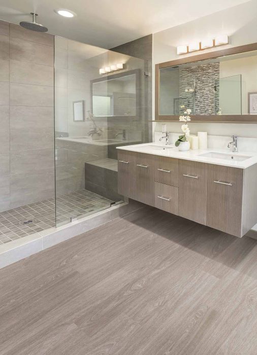 bathroom with waterproof luxury vinyl floors and a tile shower